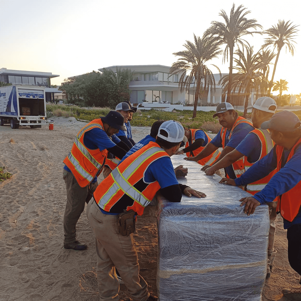 Team handling wrapped furniture on beach